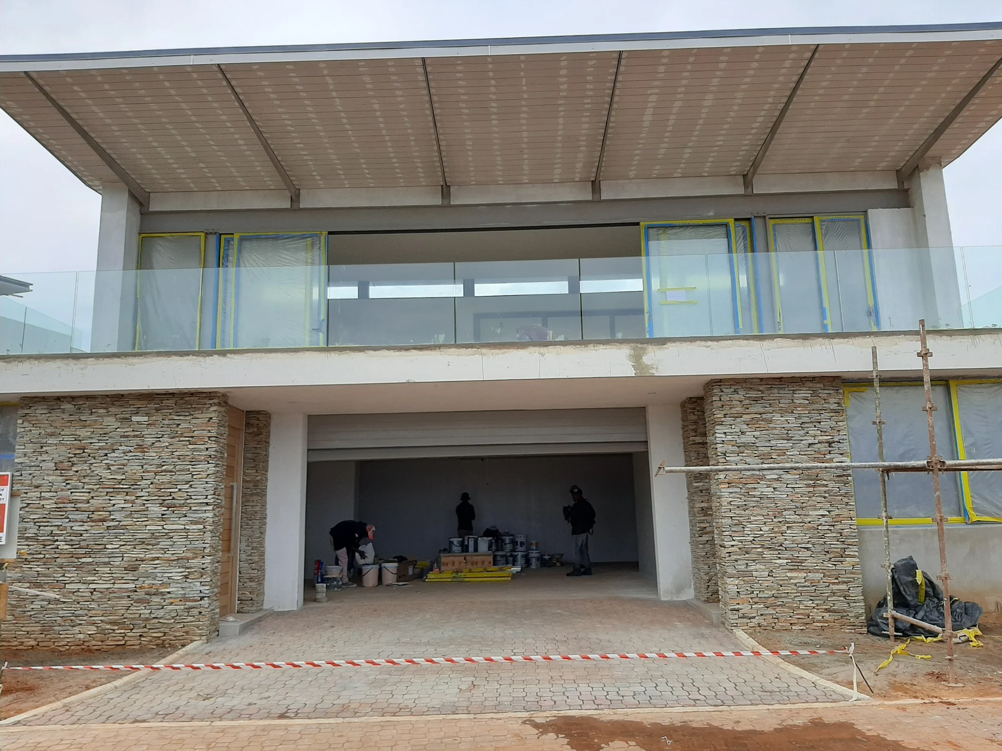 Completed two storey residence with stone cladding, glazing and a broad roof overhang