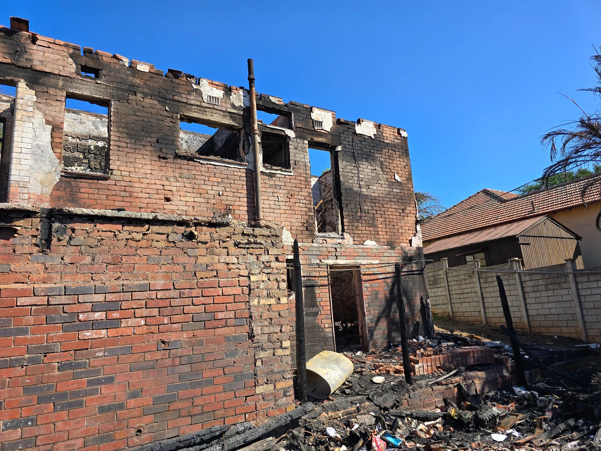 Fire damaged brick building with destroyed roof and debris