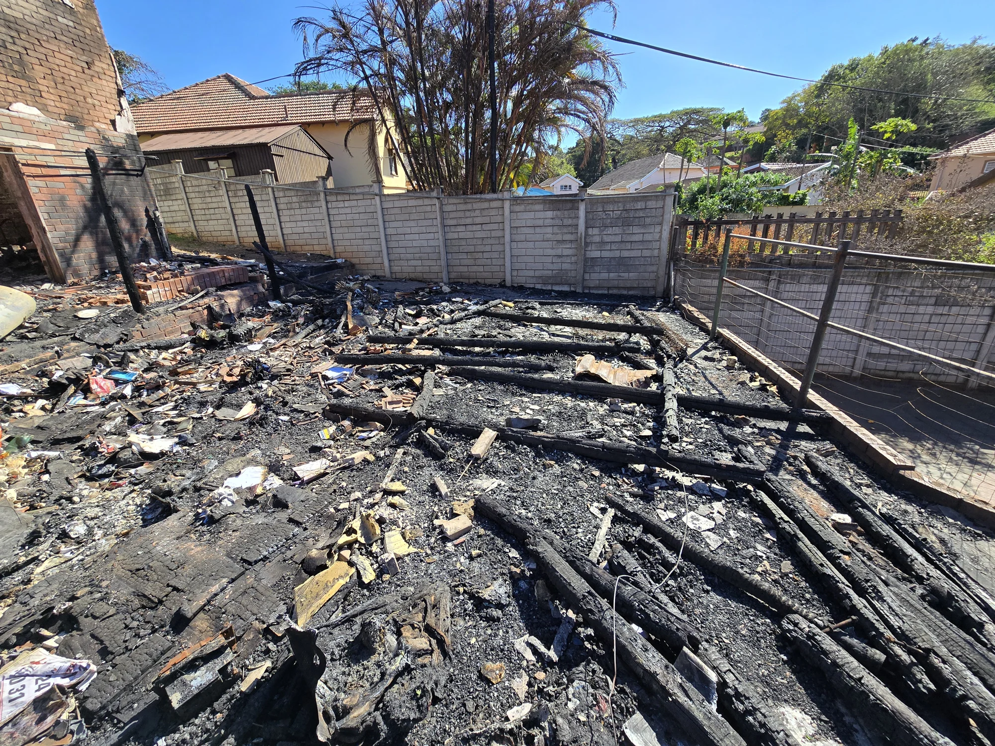 View across burned roof timbers and debris within a damaged building
